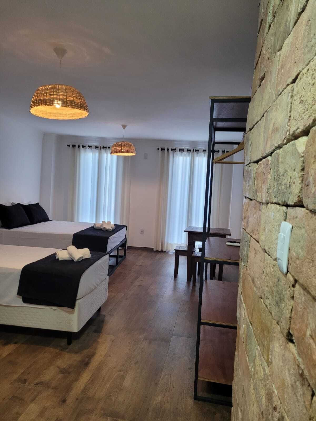 Una camera d'albergo con due letti, un tavolo da pranzo e un muro in mattoni.