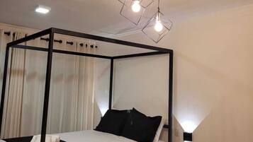 Un dormitorio moderno con una cama con dosel, una pequeña mesita de madera y una lámpara de techo original.