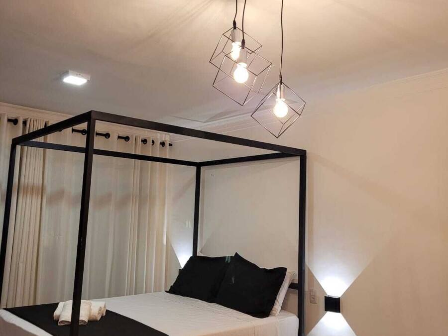 Un dormitorio moderno con una cama con dosel, una pequeña mesita de madera y una lámpara de techo original.