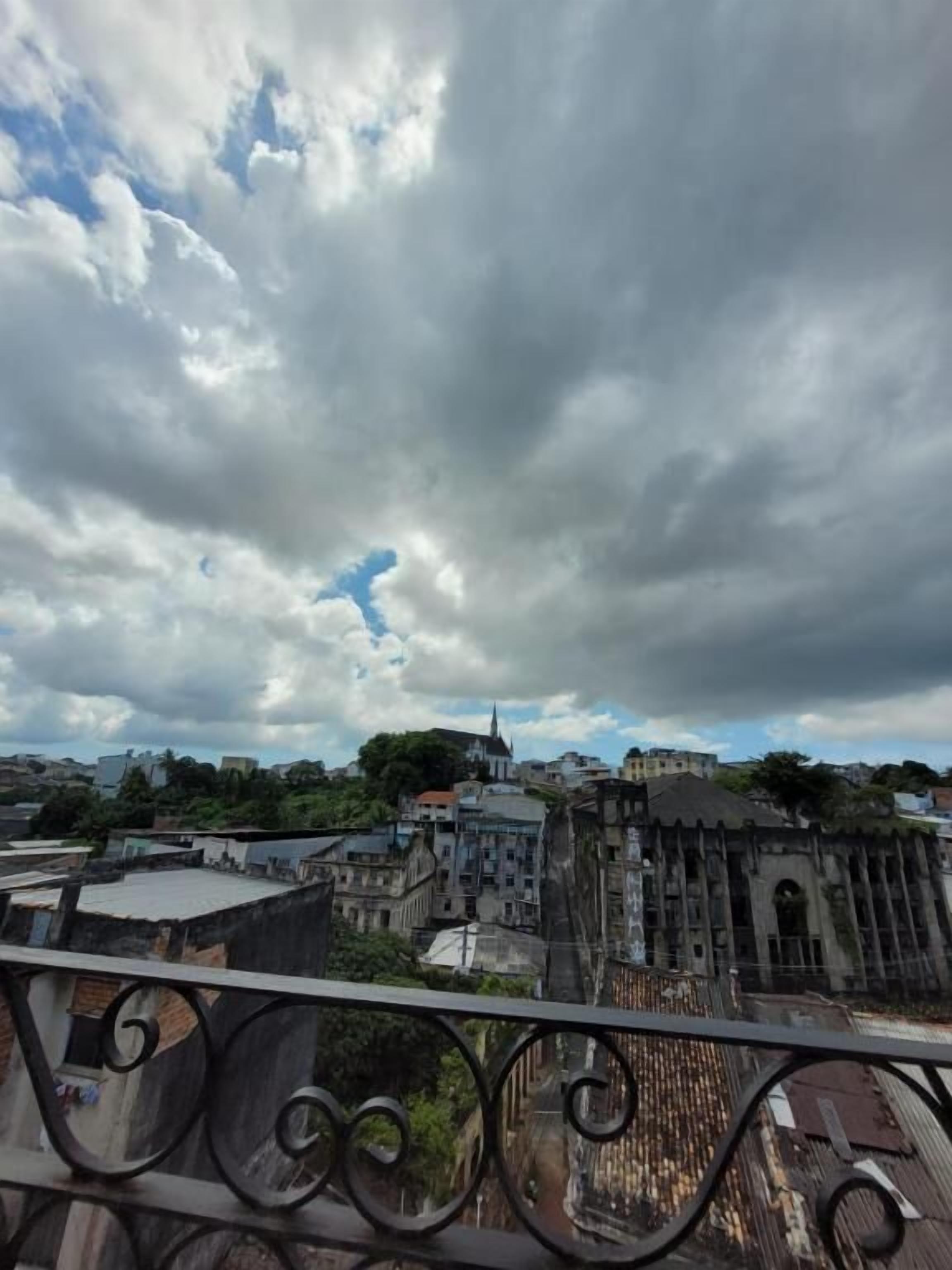 A cityscape with historical architecture, including a prominent church spire, under a cloudy sky.