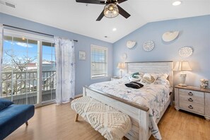 Relax in this stylish bedroom with a large bed, wooden headboard, and sliding glass door leading to a balcony with a view.
