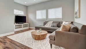 A modern living room with a grey sofa, a wooden coffee table, and a flat-screen TV on a white stand. - Next to Rainey St, Town Lake, Super Cozy with Modern Aesthetic (Austin)