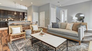 A modern living room with a grey sofa, a coffee table, and a wooden bench. - Next to Rainey St, Town Lake, Super Cozy with Modern Aesthetic (Austin)