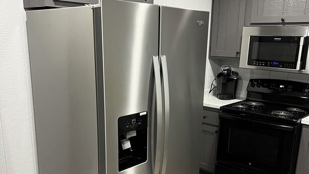 Un refrigerador de acero inoxidable con compartimento congelador, dispensador de hielo incorporado y dispensador de agua.