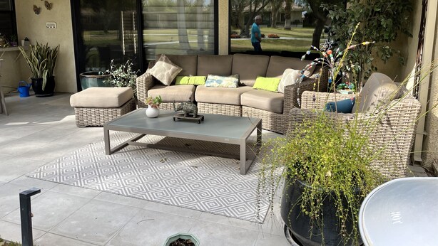 En terrasse med sofa, sofabord og plantekasser.