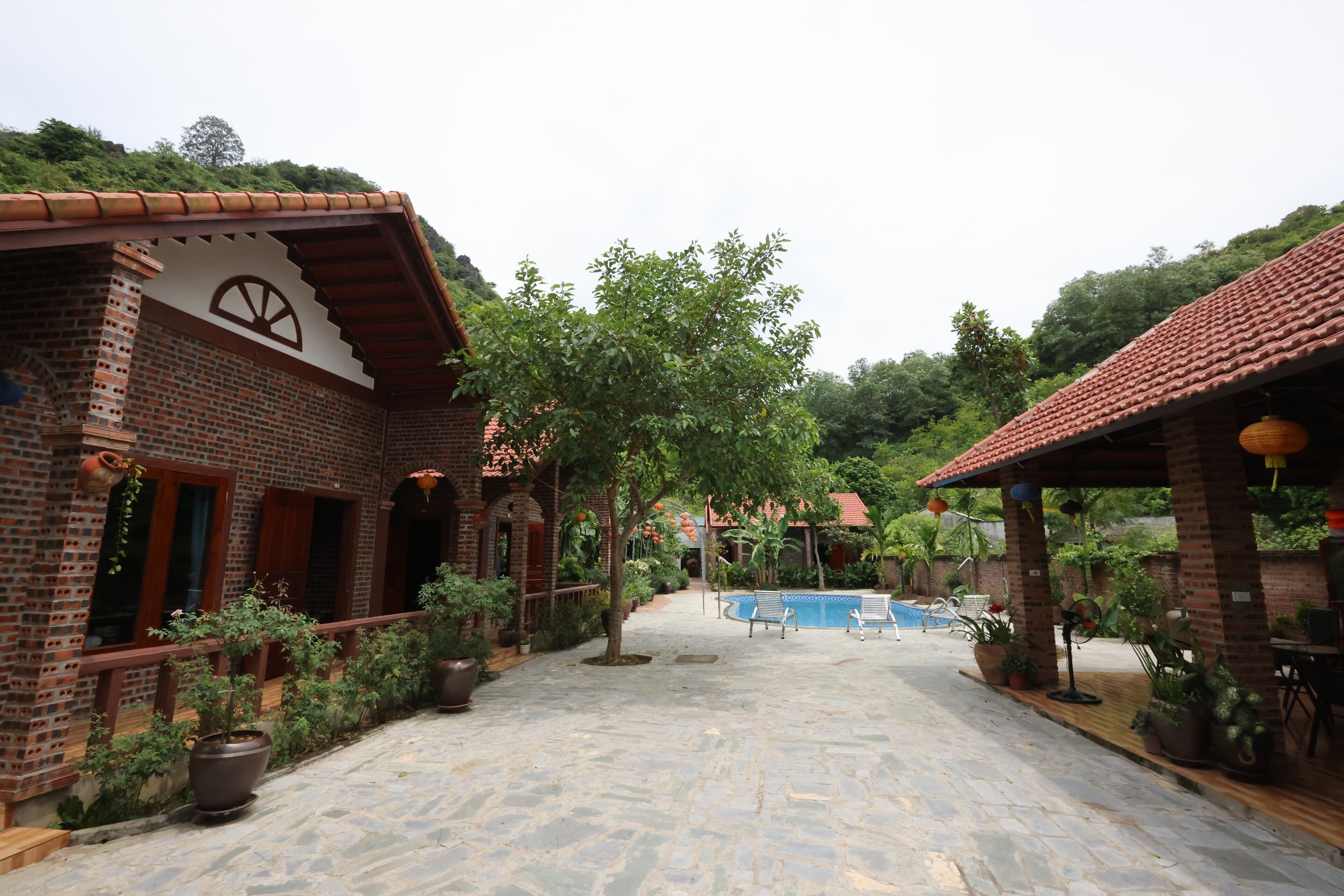 A courtyard with a swimming pool, brick buildings, and potted plants.