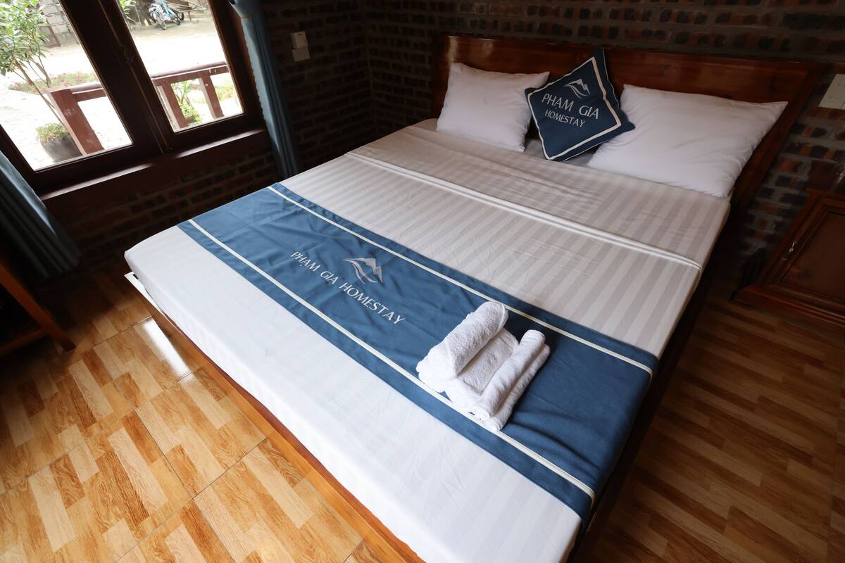 A neatly made bed with a blue and white bedspread, two pillows, and a towel.
