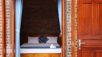 A room with a brick wall, a wooden door, and a bed with a pillow that reads "PHAM GIA HOMESTAY".