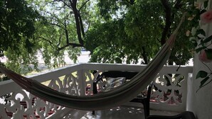 A hammock tied between white lattice railings, a black chair, and a white wall with a floral pattern. - samalinda (Santa Marta)