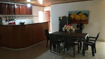 A kitchen with wooden cabinets, a dining table with chairs, and a wall-mounted fan.