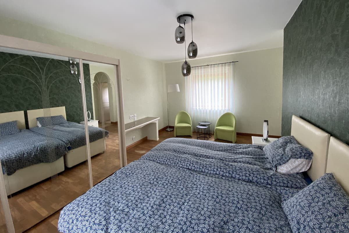Un dormitorio con una cama grande, dos sillas, una mesita y un espejo.