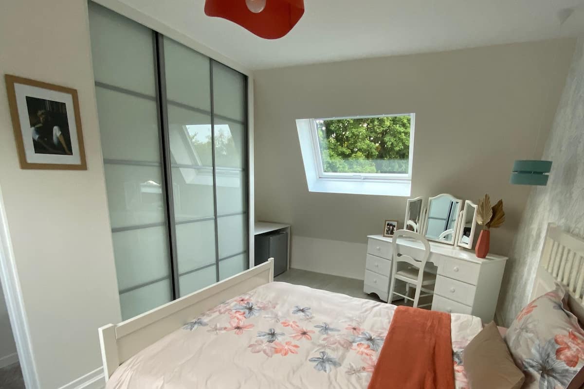 Un dormitorio con una cama, un aparador, una ventana y una puerta corredera.