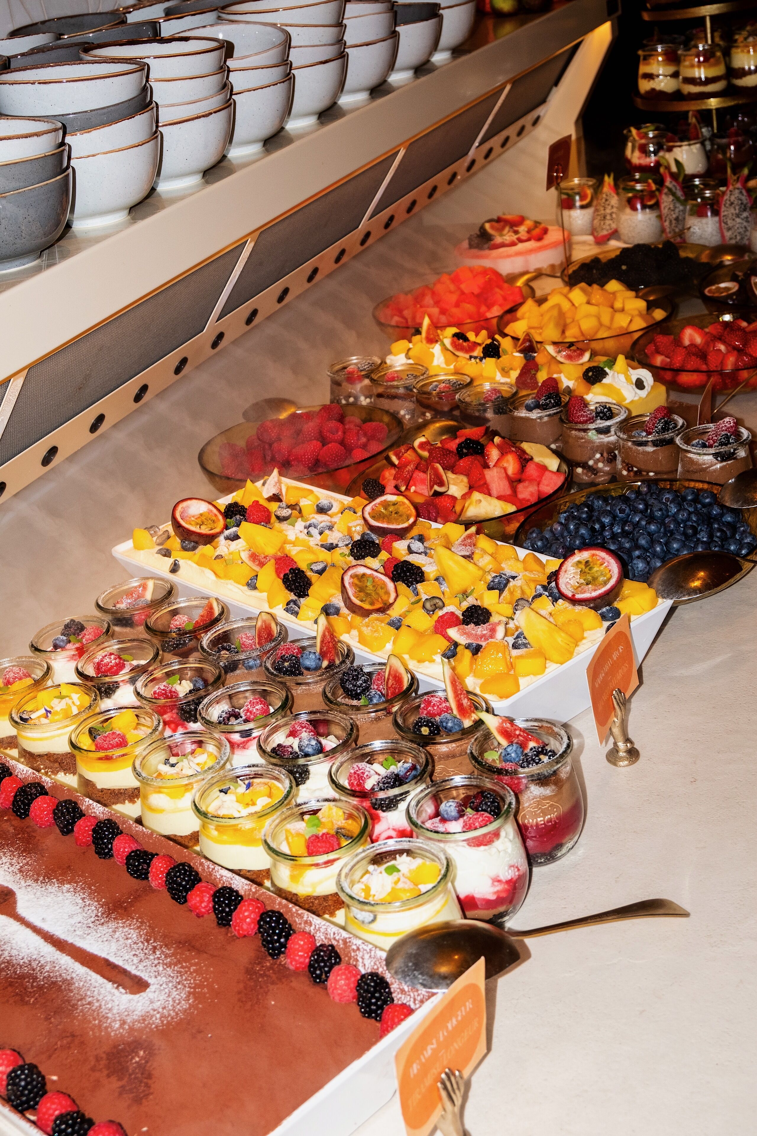Un bufé con diversas frutas, postres y bebidas.