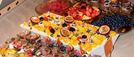 A buffet with various fruits, desserts, and beverages.