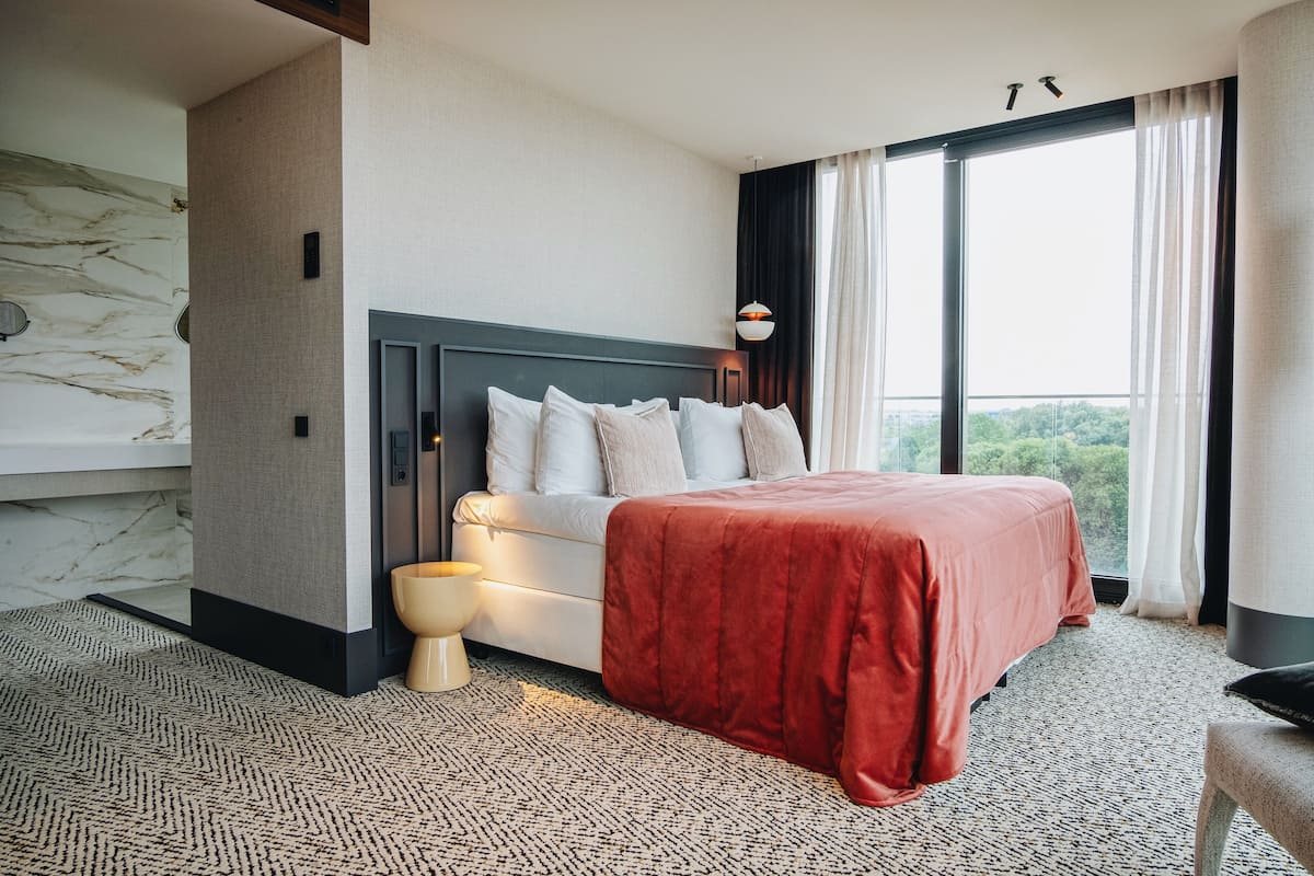 Une chambre d’hôtel moderne avec un grand lit, un mur en marbre et une vue sur l’extérieur.