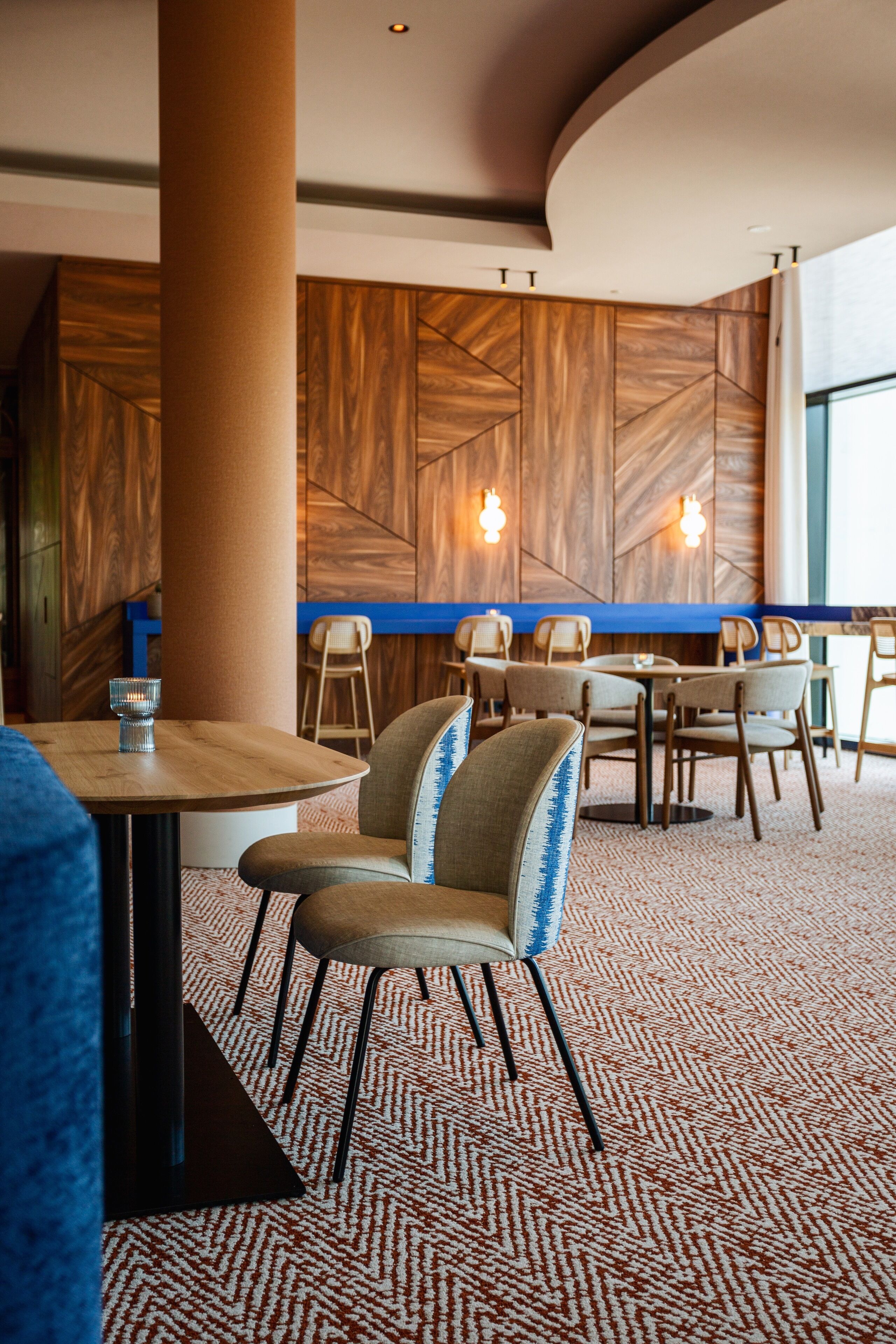 Un intérieur de restaurant moderne avec des murs lambrés, des tables rondes et des chaises.