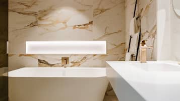Un baño moderno con una bañera independiente, un lavabo aparte y paredes de mármol.