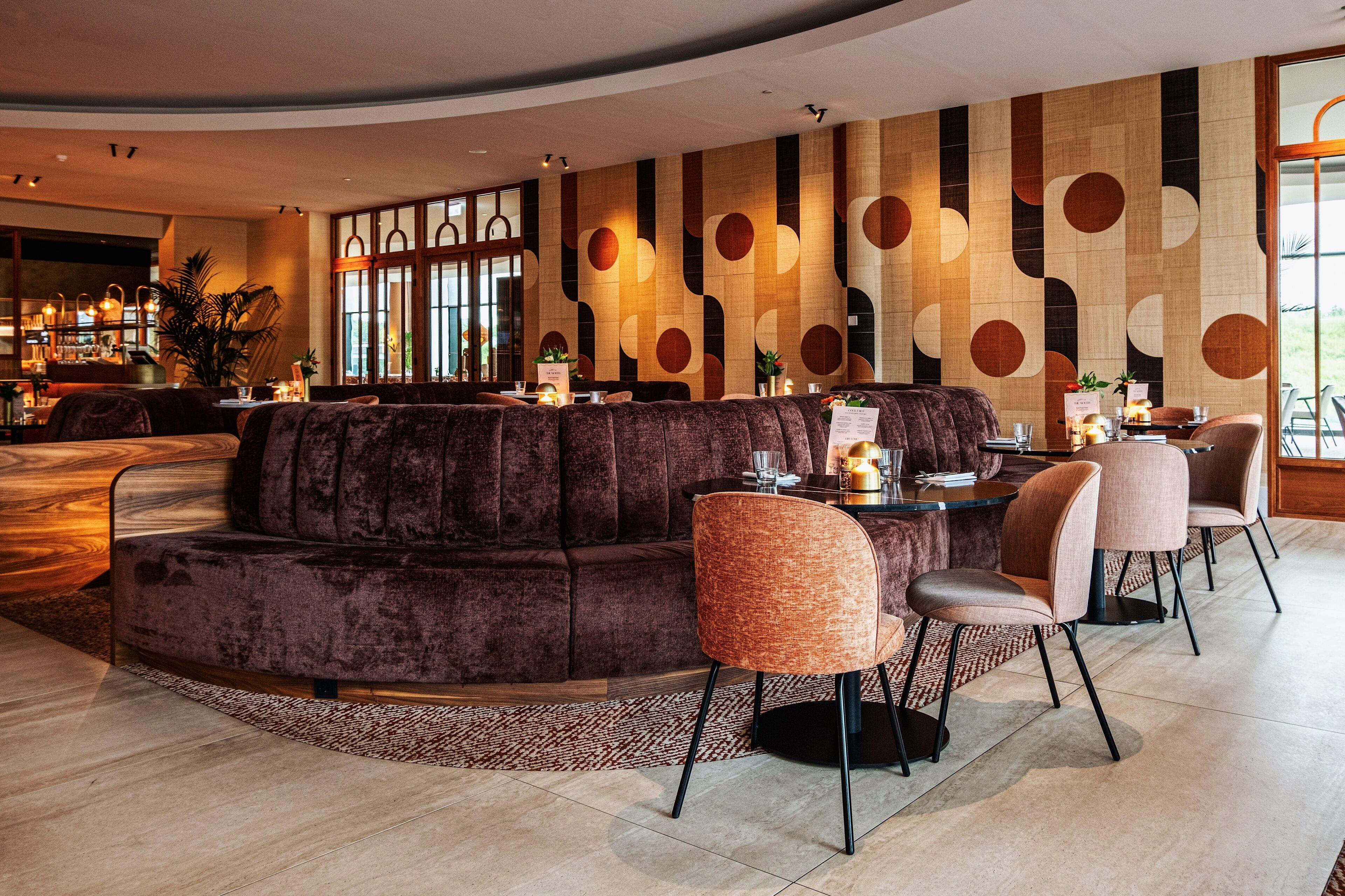 Ein stilvoller Lounge-Bereich mit einer gebogenen Couch, Sitzmöglichkeiten und einer Bar.