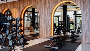 Un gimnasio moderno con paredes de madera, arcos espejados y diversos equipos de ejercicio.