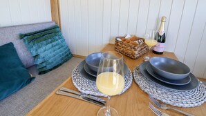 Een eettafel gedekt met borden, kommen, bestek en een glas wijn.
