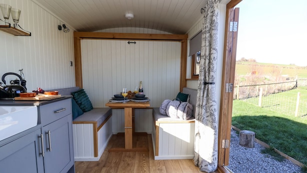 Een kleine keuken met een houten tafel, een bank en uitzicht op de omgeving.