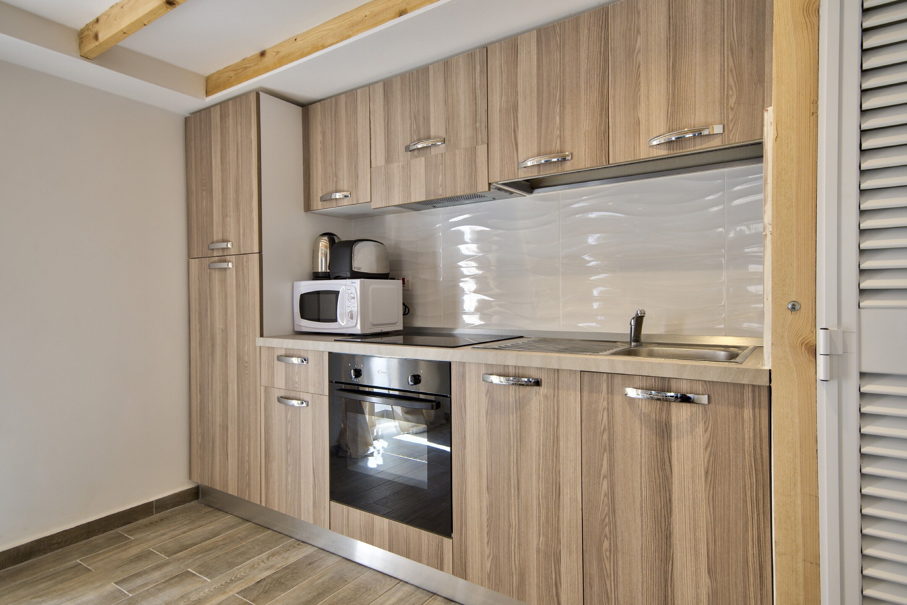 Una cocina moderna con armarios de madera, horno empotrado y microondas.