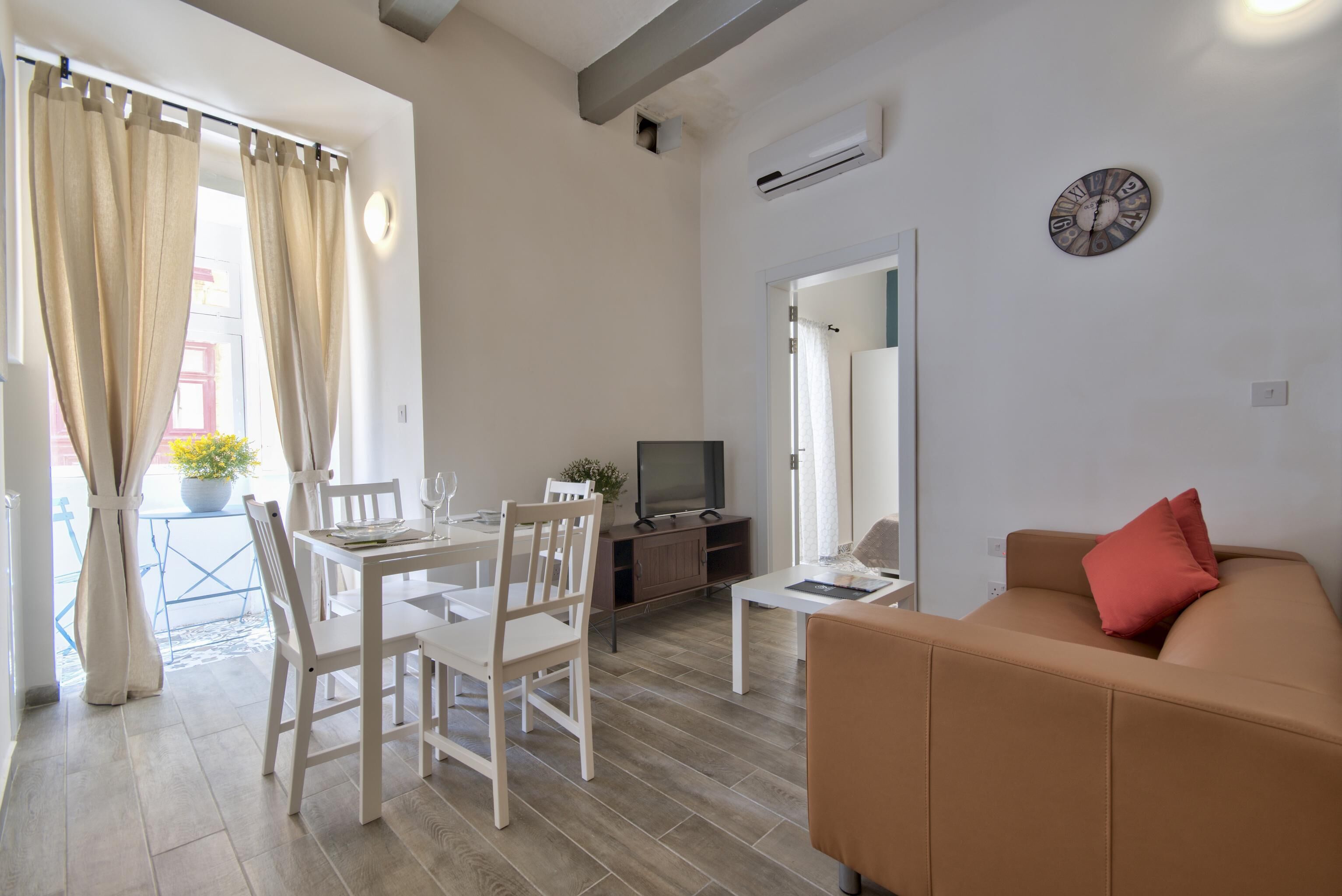 Un salon comprenant un canapé, un téléviseur et un coin repas avec des chaises et une table.