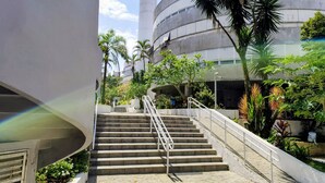 A staircase leading to a building with a curved facade and a cylindrical tower. - 01E Vista Linda Pe Areia Guaruja - Tombo (Guarujá)