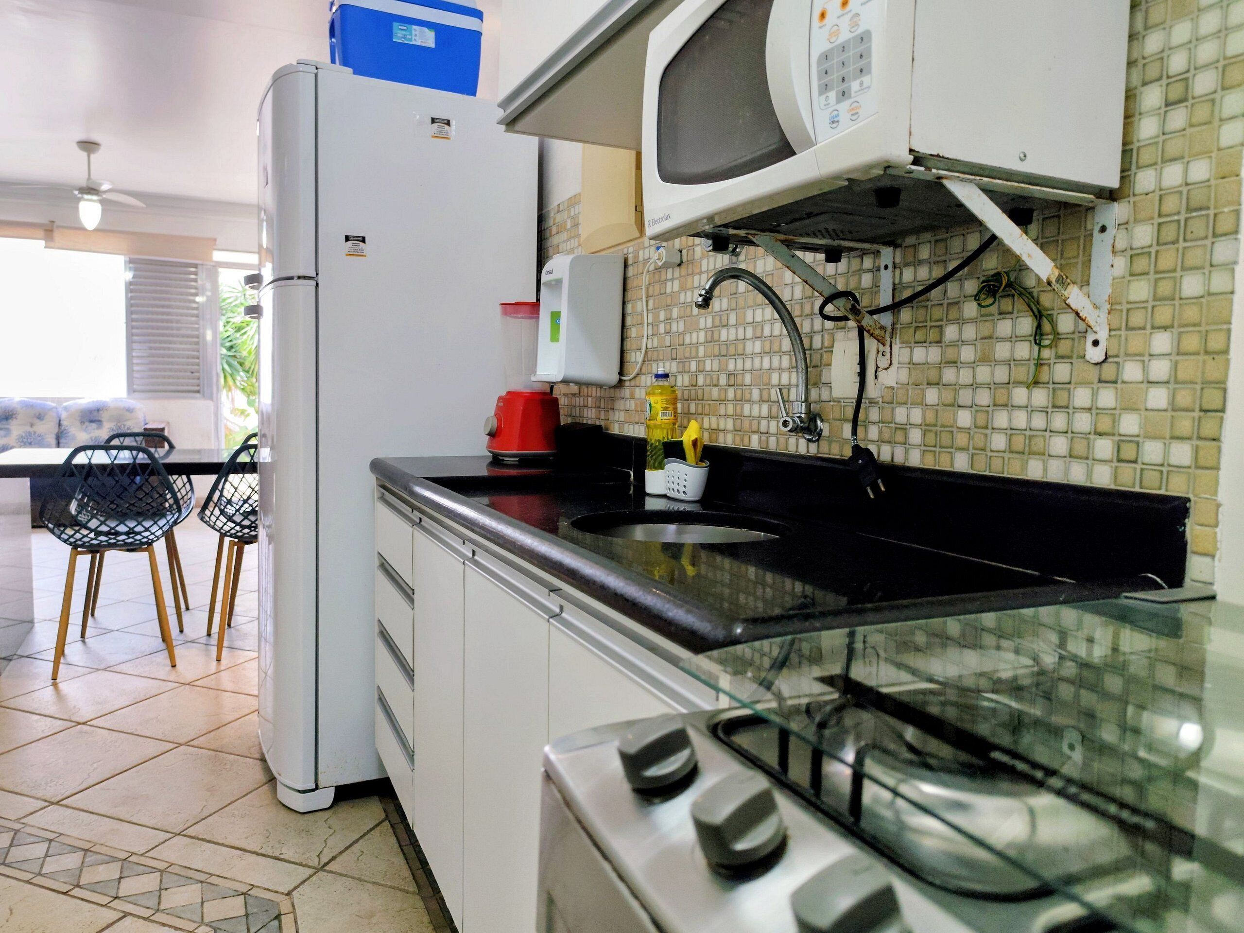 Een keuken met een koelkast, magnetron, fornuis en spoelbak.
