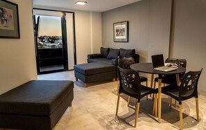 A modern living room with a sofa, ottoman, and a dining table with chairs. - Midhouse Smartflat (Córdoba)