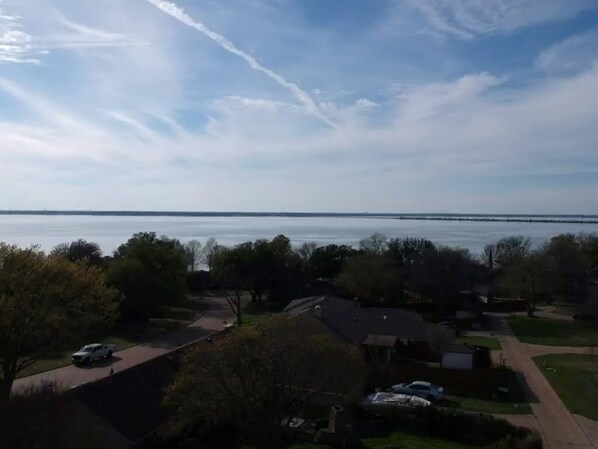 A residential area with houses, a road, and a body of water in the background.