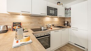 A modern kitchen with white cabinets, a Bosch oven, a microwave, and a sink.