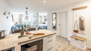 A modern kitchen with a wooden countertop, a built-in oven, and a dining area with a blue sofa.