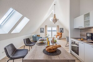 A modern loft apartment with a dining area, kitchen, and seating space.