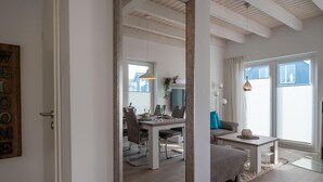 Una sala de estar moderna con comedor, ventanas amplias y techo de madera.