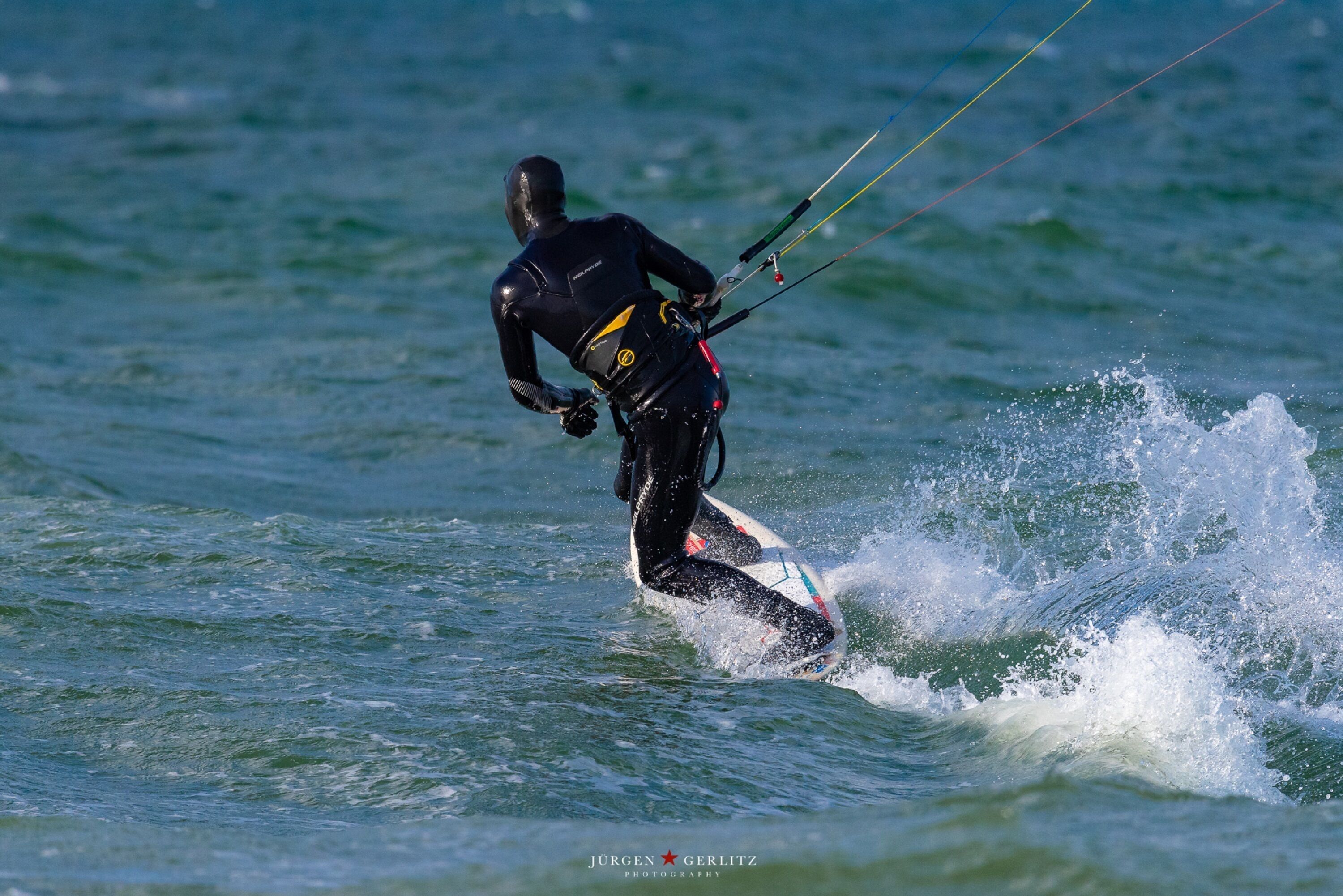 Eine Person windsurft auf einem Surfbrett im Meer.