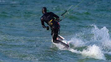 Eine Person windsurft auf einem Surfbrett im Meer.