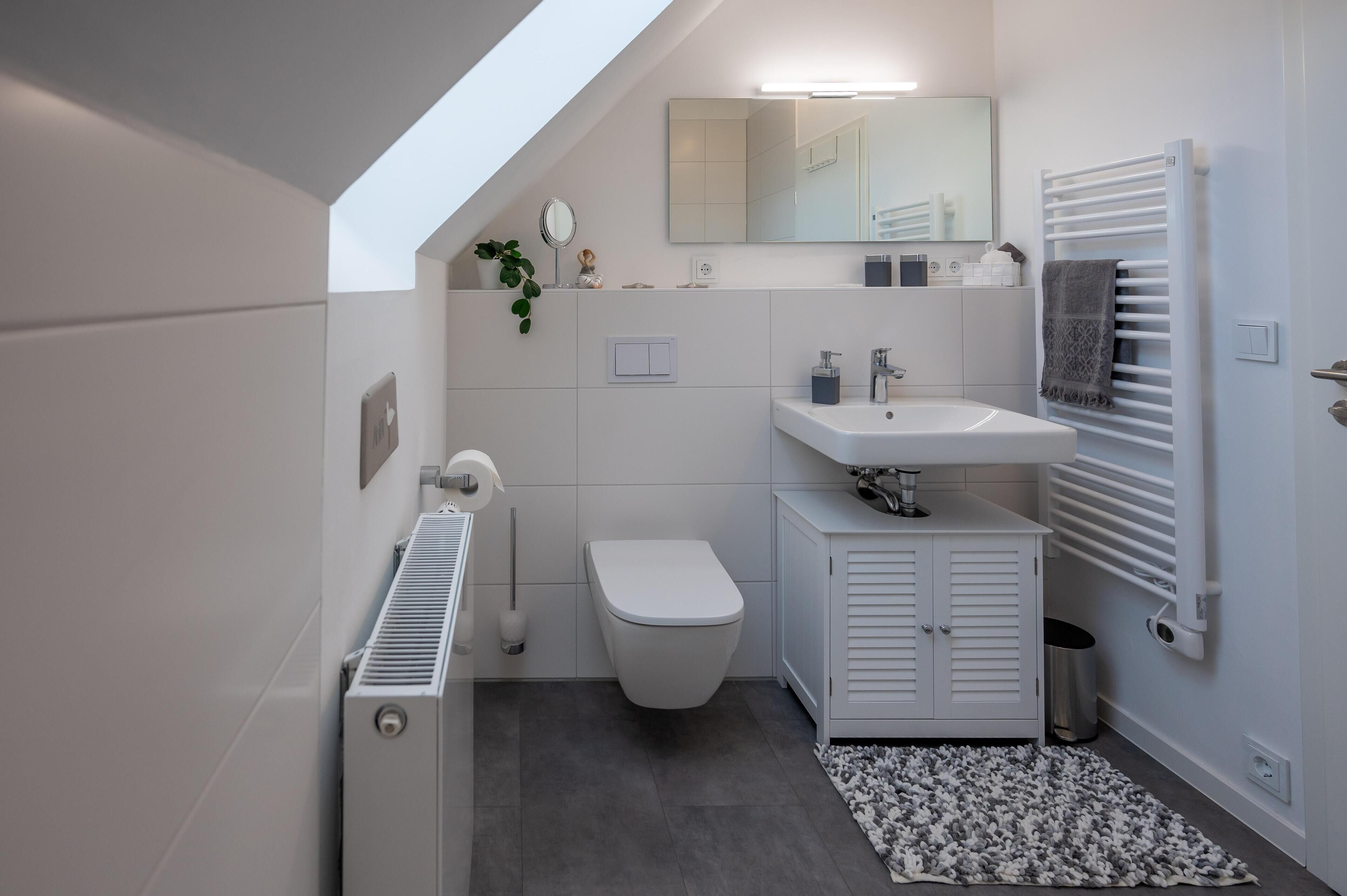 A modern bathroom with a white toilet, a sink, and a towel rack.