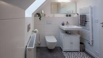A modern bathroom with a white toilet, a sink, and a towel rack.