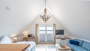 Una stanza accogliente e ben illuminata con un letto, una scrivania, un divano e una TV.