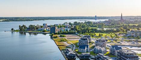 Luchtbeeld van een stad aan de rivier, met moderne gebouwen, een kerktoren en een jachthaven.