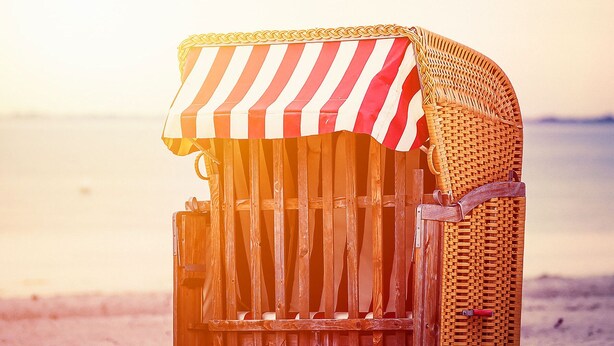 A beachside wooden structure with a striped awning, likely a beach hut or cabana.