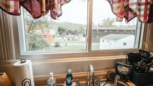 Una cocina con ventana, lavamanos y vistas a un patio y edificios.