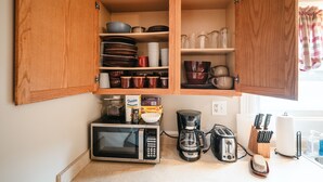 Una cocina con armarios de madera, microondas, cafetera y tostadora.