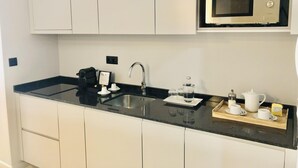 Une cuisine moderne dotée d’un plan de travail noir, d’un évier en acier inoxydable et d’un four à micro-ondes encastré.