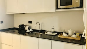 A modern kitchen with white cabinets, a stainless steel sink, a microwave, and a coffee station. - Downtown 2B in Oporto (Porto)