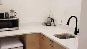 A compact kitchen with a microwave, coffee maker, and sink. - Rainforest Lane Loft suite (Ucluelet)