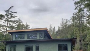 A two-story house with a garage, a small porch, and a deck. - Rainforest Lane Loft suite (Ucluelet)