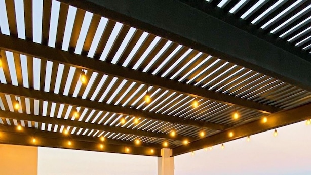 Un patio al aire libre con mobiliario de mimbre y luces colgantes, con vista al mar.