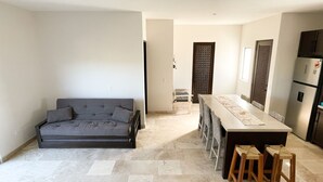 Un espacio de estar moderno con sofá, mesa de comedor, sillas y zona de cocina.